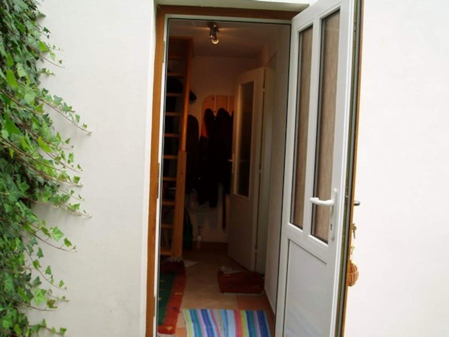 Otevřené vchodové dveře, za nimi chodba se schody